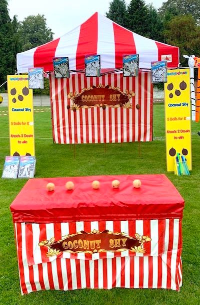 Coconut shy with red and white stripey decor, set up in a field ready to play